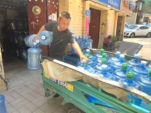 一名送水工人在搬运大桶水